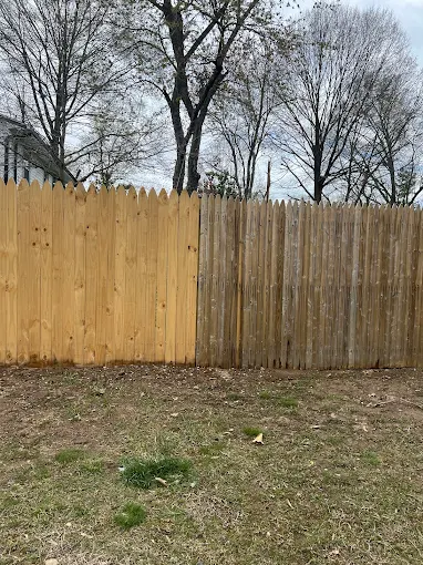 Wooden fence with two different shades, bare trees in background