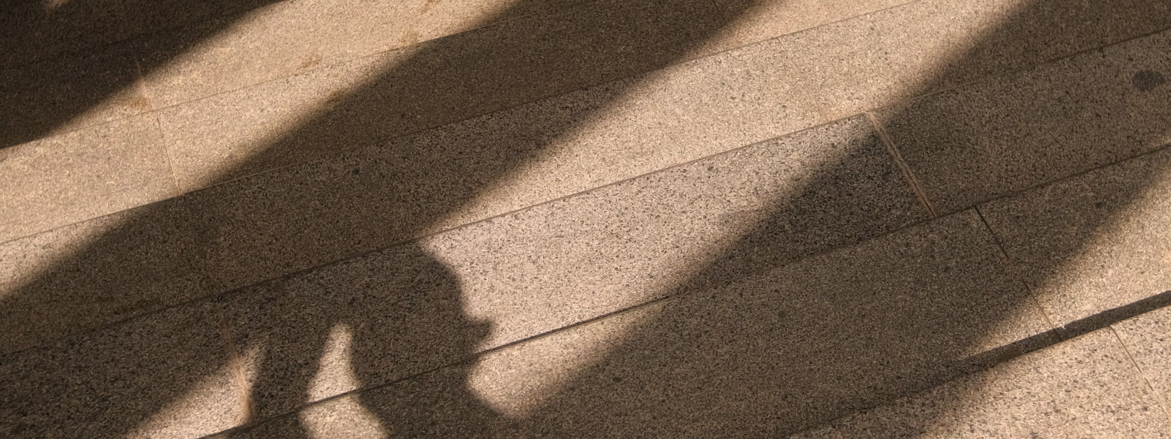 Textured surface with diagonal shadows cast across tiled floor