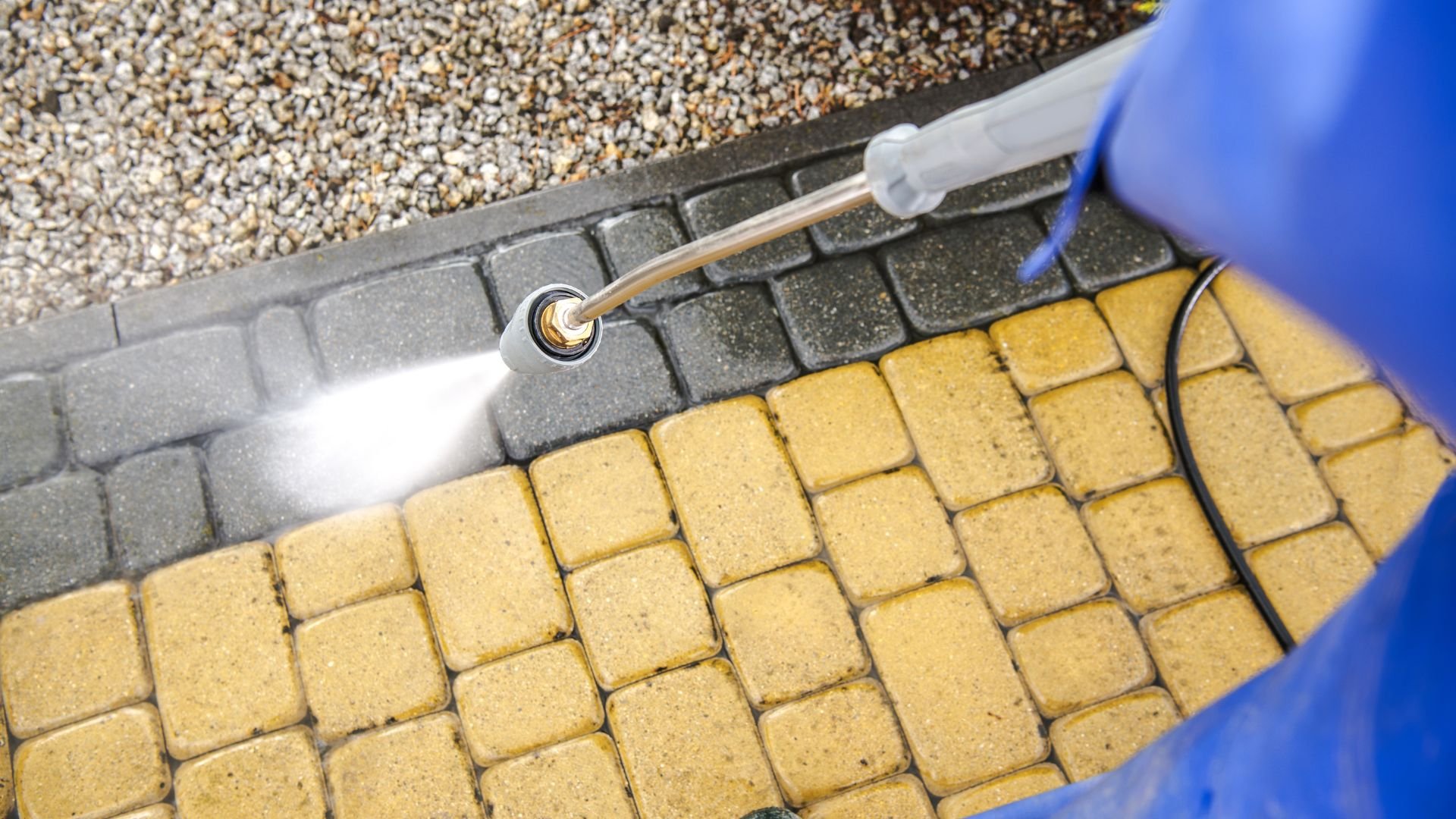 Pressure washer cleaning yellow brick pavement with water spray